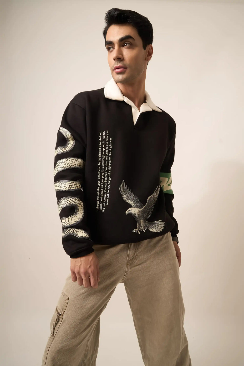 Man wearing a black sweatshirt with eagle  and serpent design on a plain background