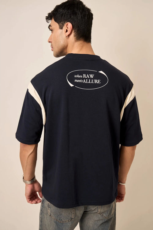 Man wearing a navy t-shirt with text design on the back against a beige background