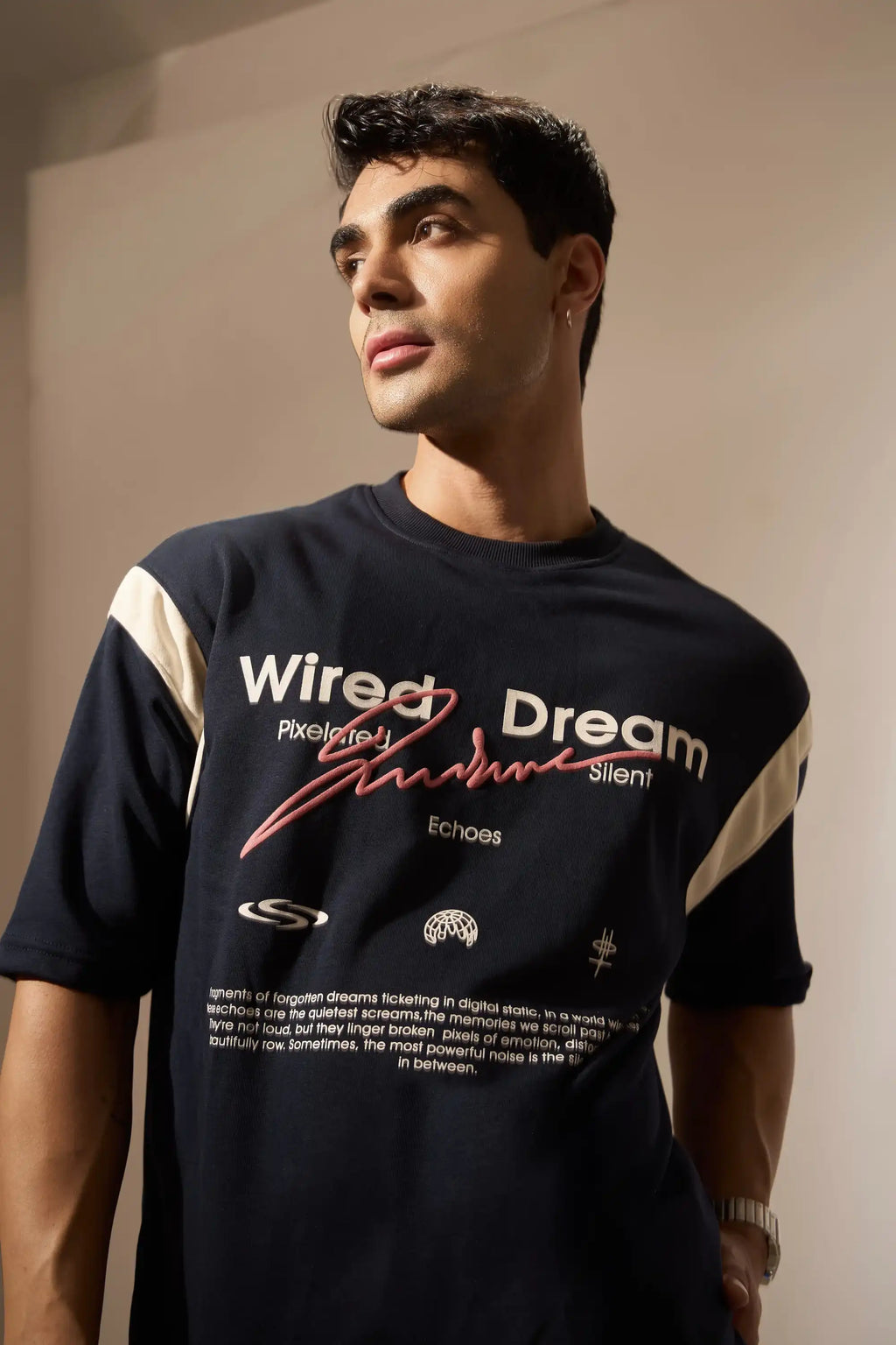 Man wearing a navy t-shirt with text and design against a neutral background