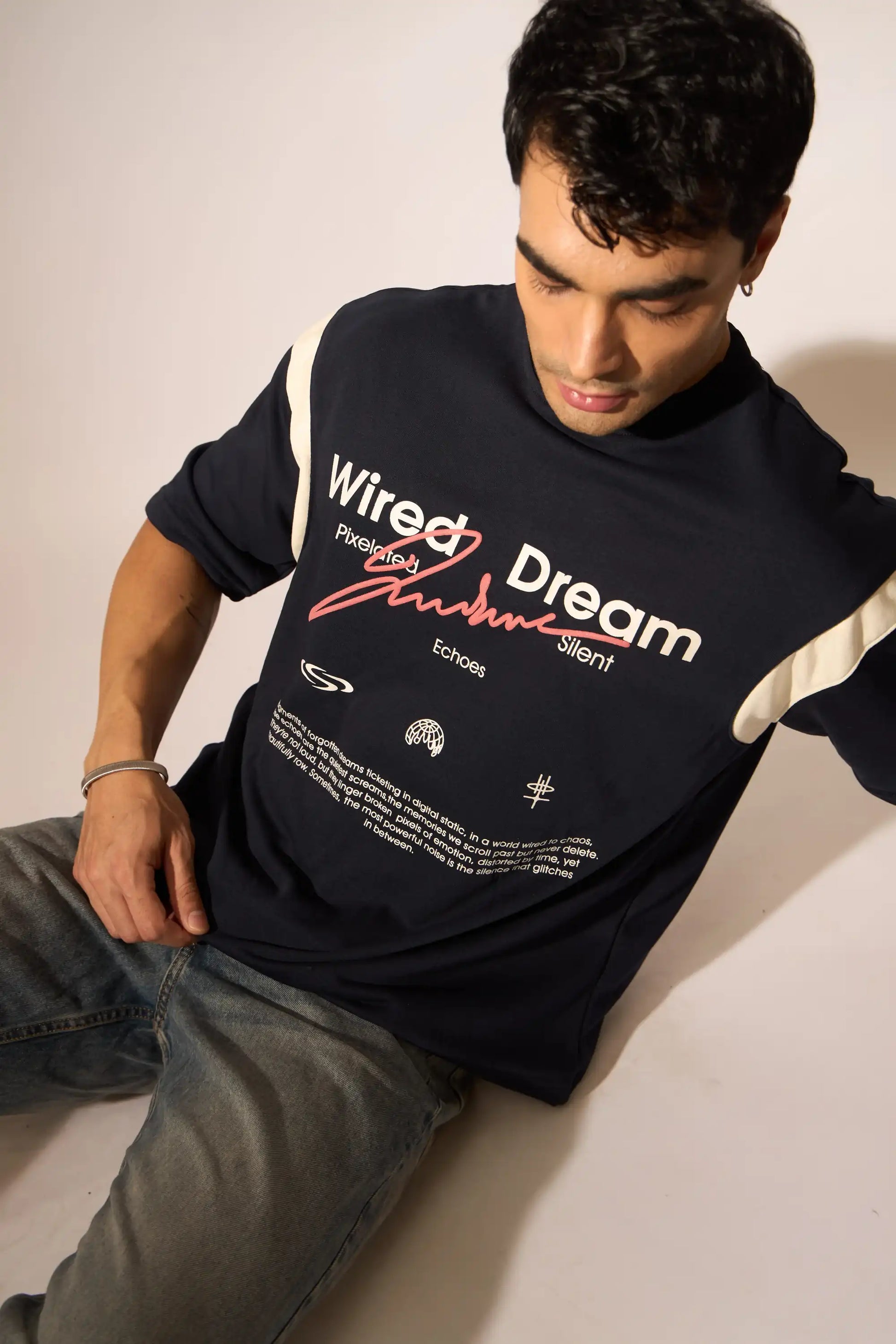 Person wearing an oversized navy t-shirt with text and graphics on a plain background
