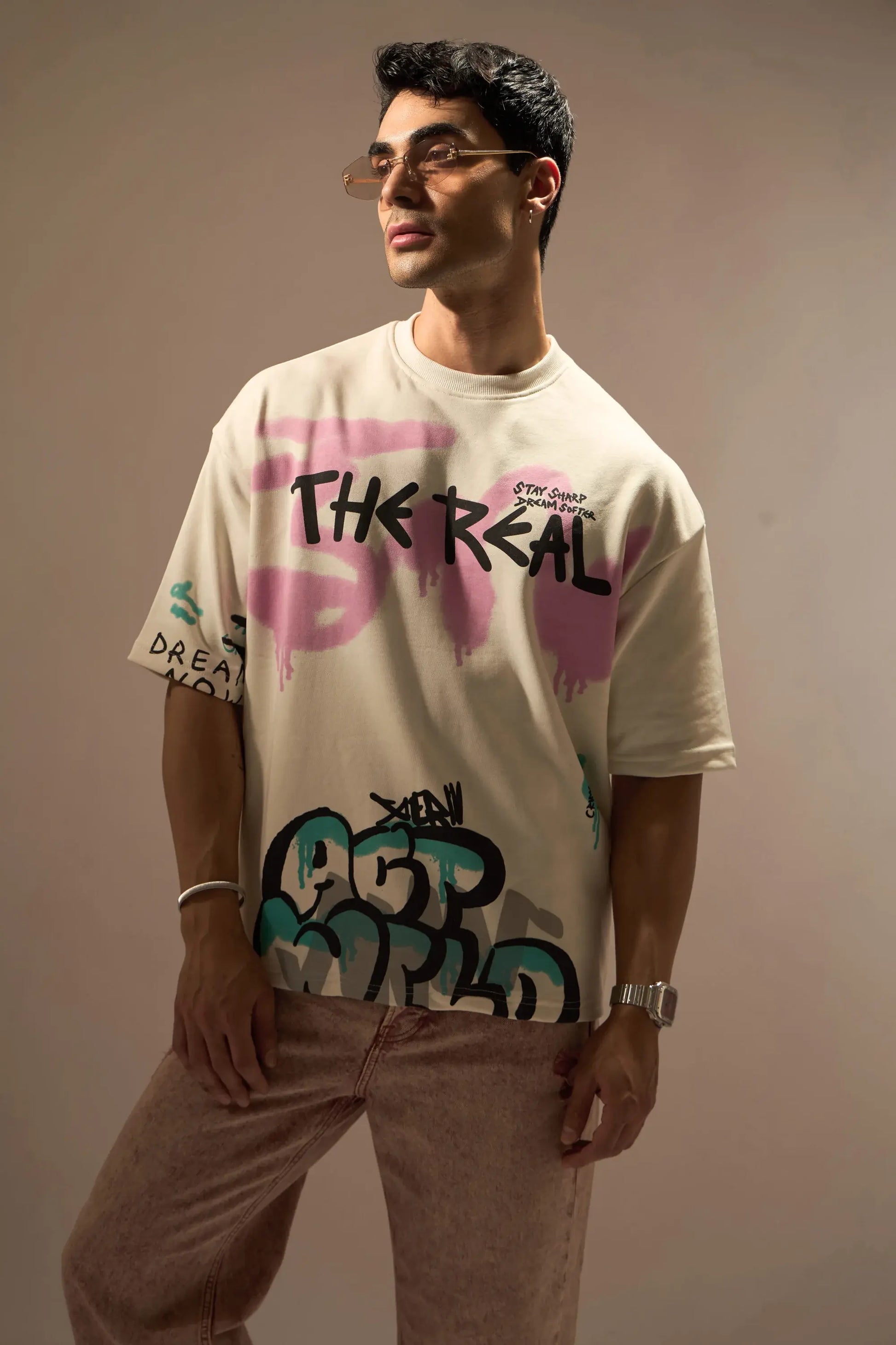 Person wearing a white t-shirt with colorful text and graphics on a plain background